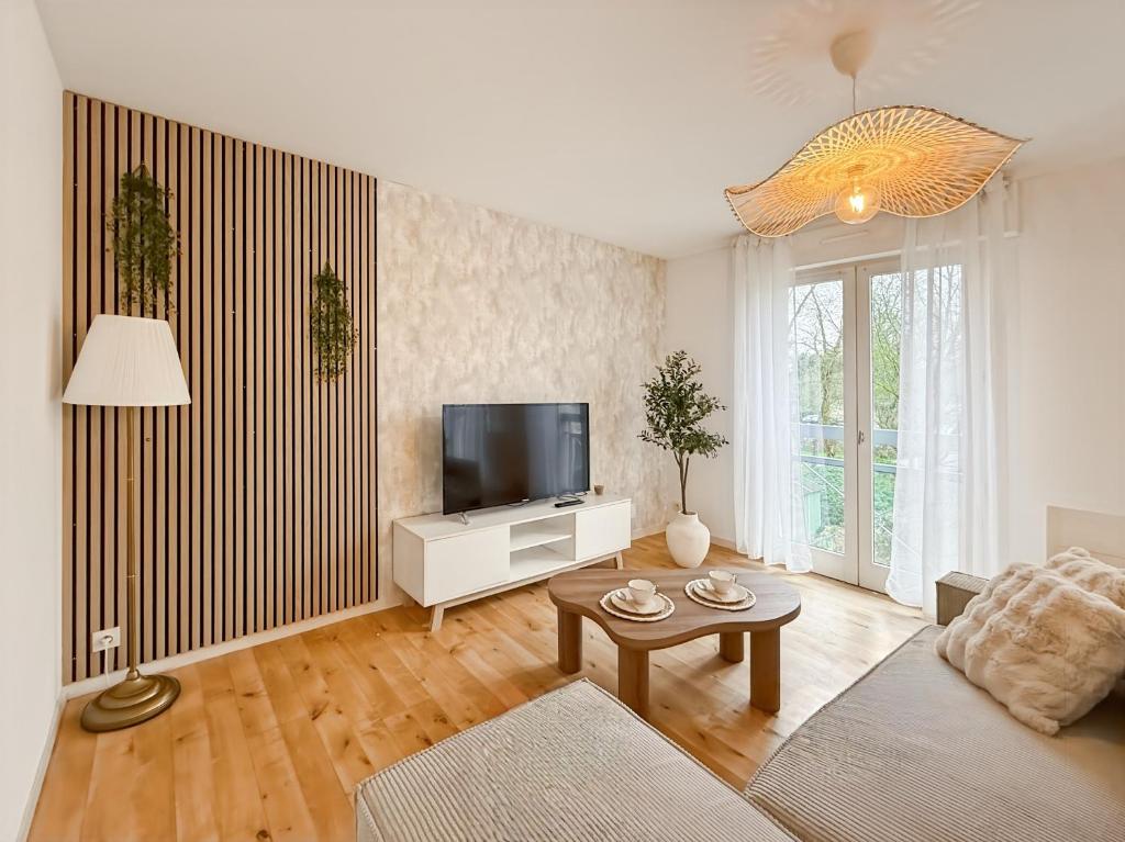 a living room with a couch and a tv at L'Ecrin - Spacieux & Garage Privé - Calme à 5minutes de Rennes in Pacé