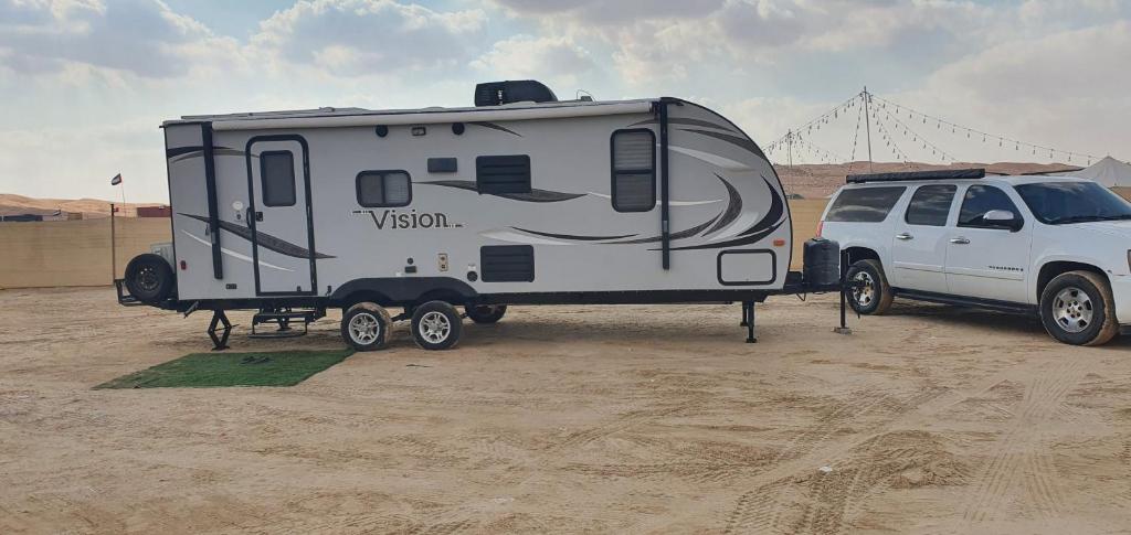 a camper parked next to a white van in the desert at مخيم السراي الشتوي in ‘Ibrī
