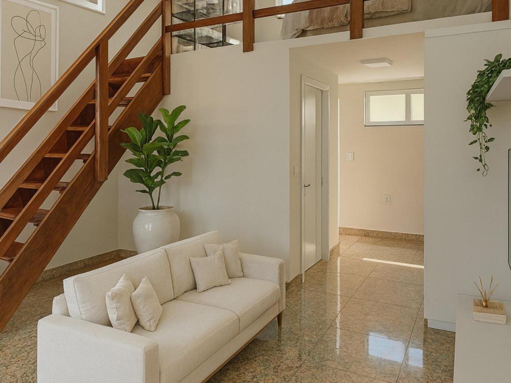 a living room with a white couch and stairs at Cataratas Loft Residence in Foz do Iguaçu