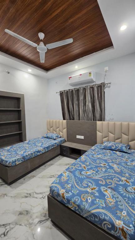 een slaapkamer met twee bedden en een plafondventilator bij Deoghar BnB Homestay in Deoghar