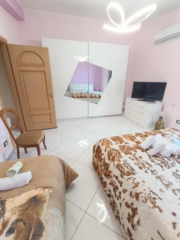 a bedroom with two beds and a flat screen tv at PERLA VERDE Suites in Patti