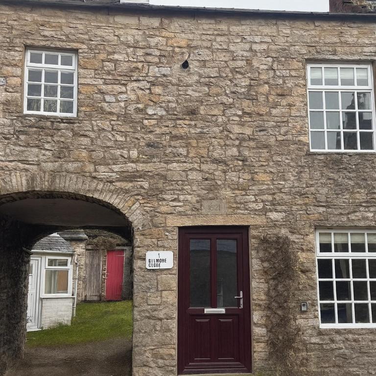 a stone building with a door and two windows at 1 Gilmore Close in Alston