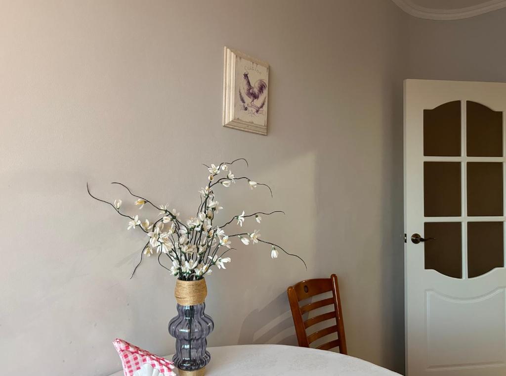 a vase with flowers in it sitting on a table at Minimalist 2-room Apartment in Aktobe