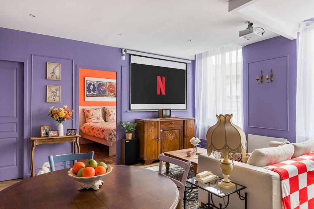ein Wohnzimmer mit lila Wänden und einem TV in der Unterkunft Appartement immersif - ambiance série TV in Saint-Étienne