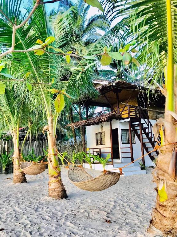 a couple of hammocks on a beach with palm trees at Diapila baybayon Sunset View in El Nido