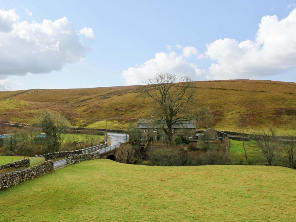 een huis in het midden van een veld met een brug bij Wain Wath Cottage in Keld