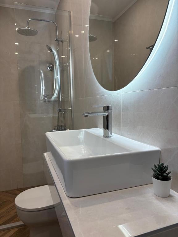 ein weißes Badezimmer mit Waschbecken und Spiegel in der Unterkunft Symposio Apartments 3 in Preveza