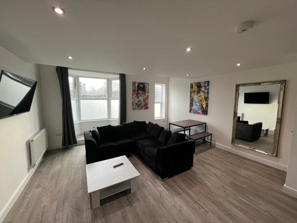 a living room with a black couch and a mirror at LT Duplex - 1 Bedroom Apartment in Leicester