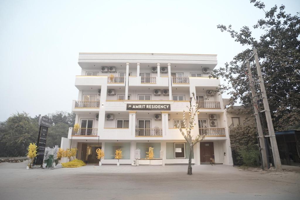 ein großes weißes Gebäude mit einem Schild darauf in der Unterkunft Amrit Residency in Gurgaon