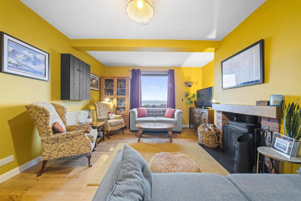 uma sala de estar com paredes amarelas e uma lareira em Beinn View 3 Bedroom House - Sea View - Ardersier em Ardersier