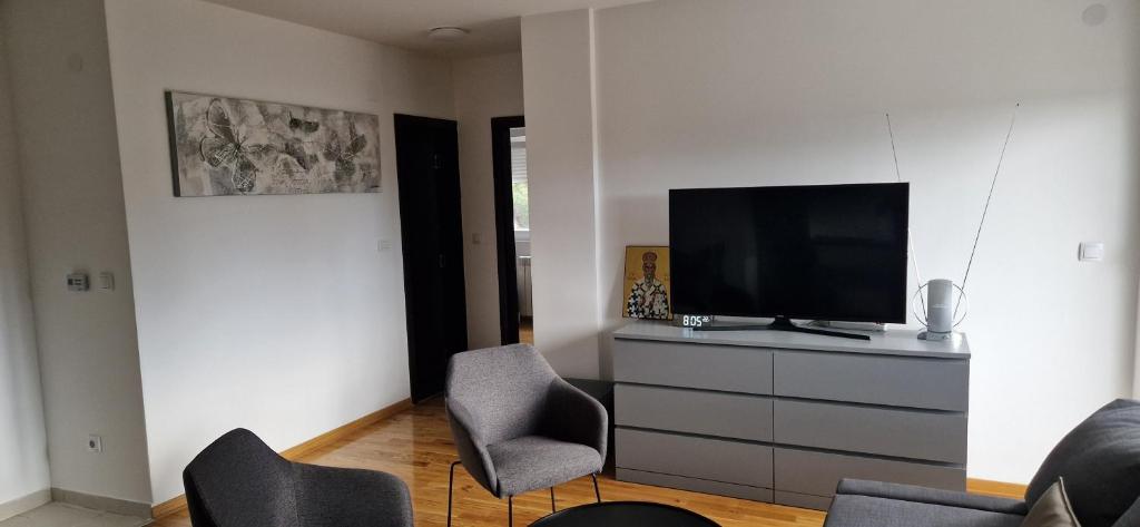 ein Wohnzimmer mit Stühlen und einem Fernseher auf einer Kommode in der Unterkunft ETA Apartments in Belgrad