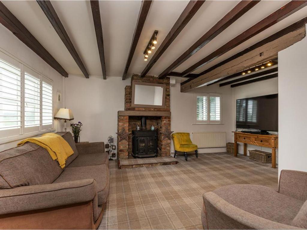 un soggiorno con divano e camino di Silver Cottage a Scruton