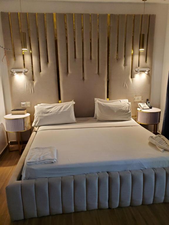 a large white bed in a room with two tables at TOUR EIFFEL HoTEL BENIN in Porto-Novo