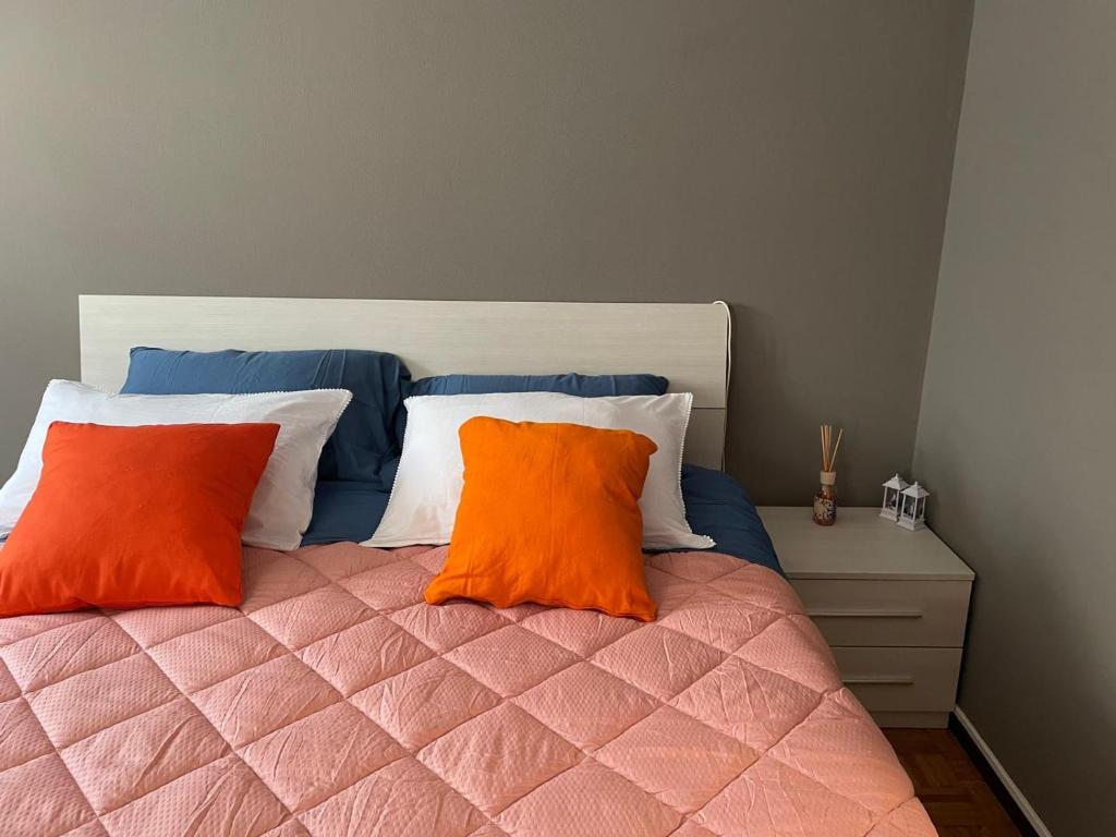 Una cama con dos almohadas naranjas encima. en Casa Silvia, en Chambave