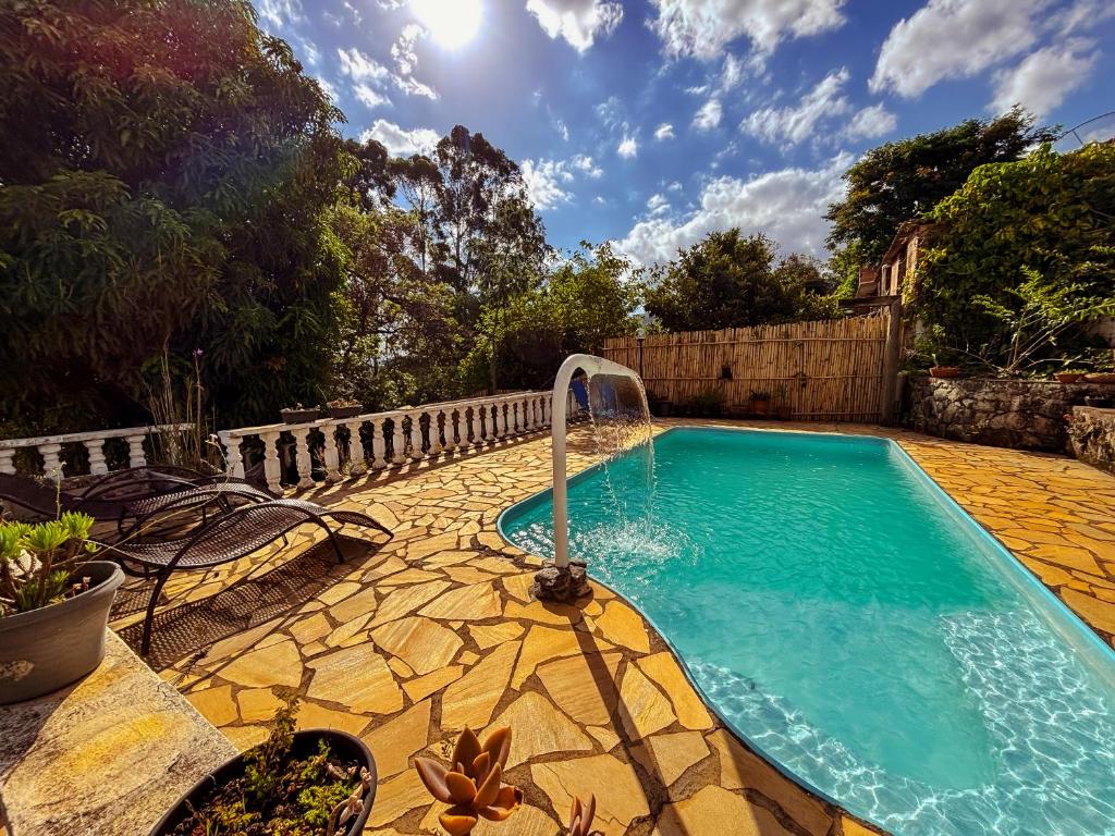 a swimming pool with a fountain in a backyard at Pousada Travessias in Tiradentes