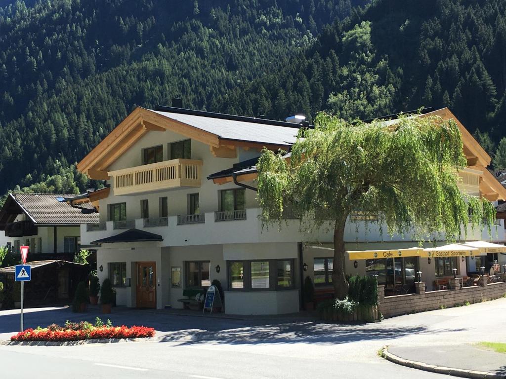 ein Gebäude mit einem Baum vor einem Berg in der Unterkunft Gasthof Sportalm in Neustift im Stubaital