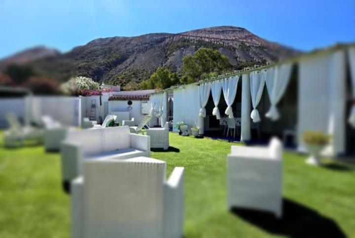 a white fence in a yard with a mountain in the background at I Venti di Vulcano in Vulcano