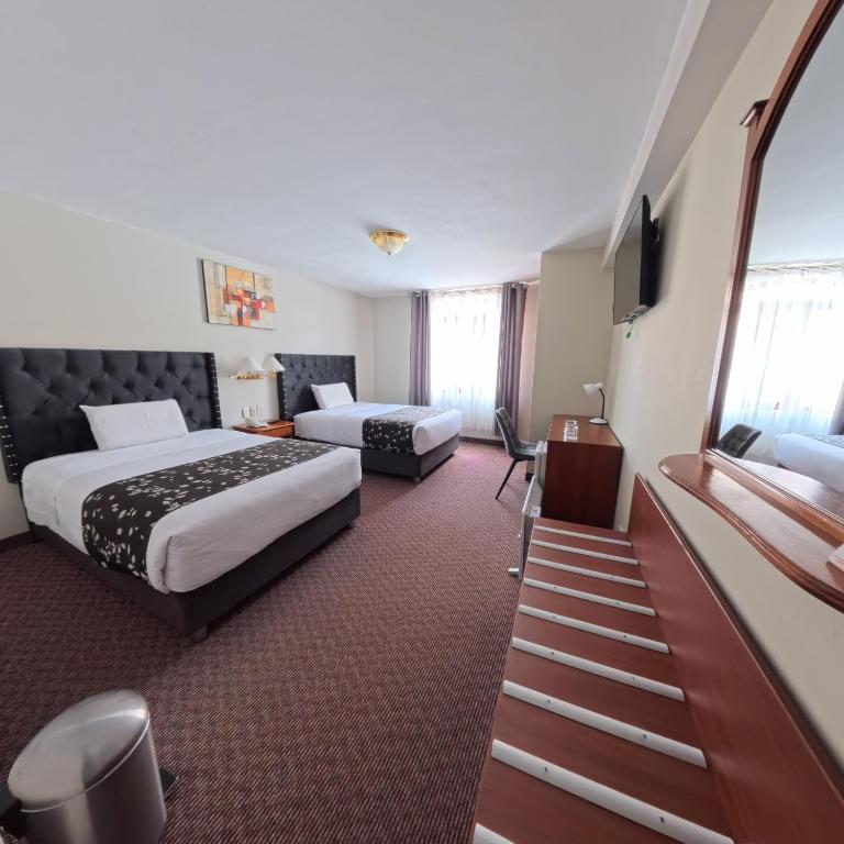 a hotel room with a bed and a couch and a television at Casona Plaza Hotel Puno in Puno
