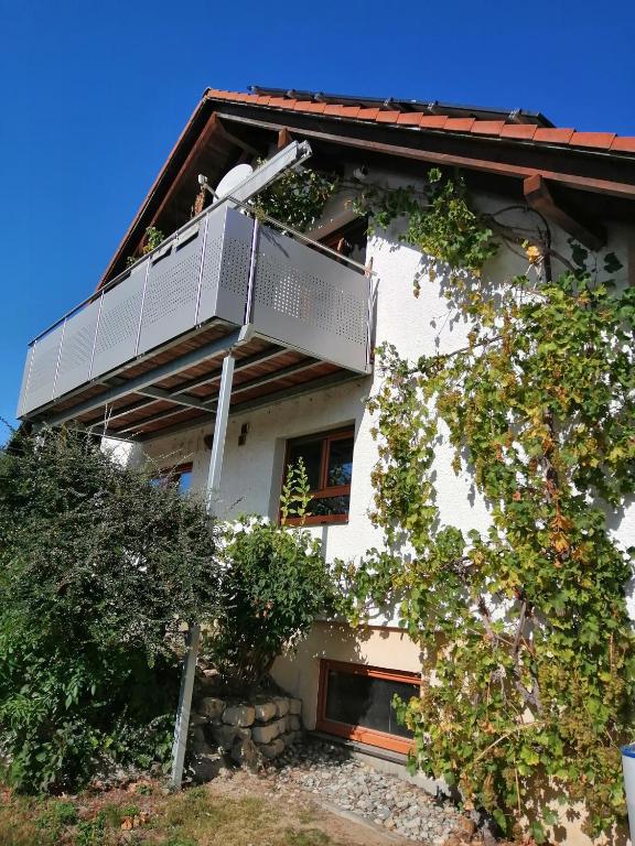 a white house with a balcony on top of it at FeWo Wacholderheide in Langenau