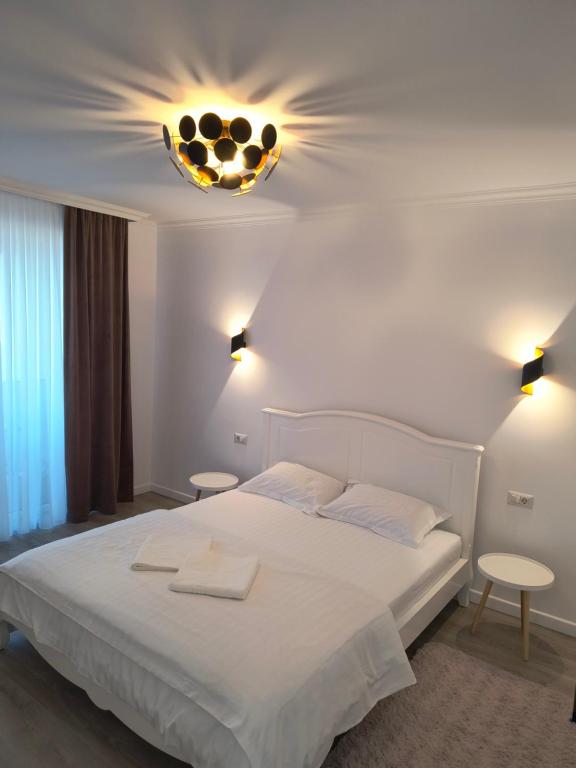 a bedroom with a large white bed and a chandelier at Twin Constantin-Apartment in Suceava