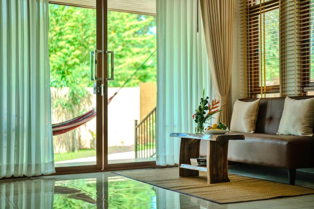 een woonkamer met een bank en een groot raam bij The Holiday Garden View in Phra Ae beach