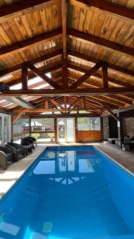 a swimming pool in a house with a wooden ceiling at Ballester's Dream in San Martín de los Andes