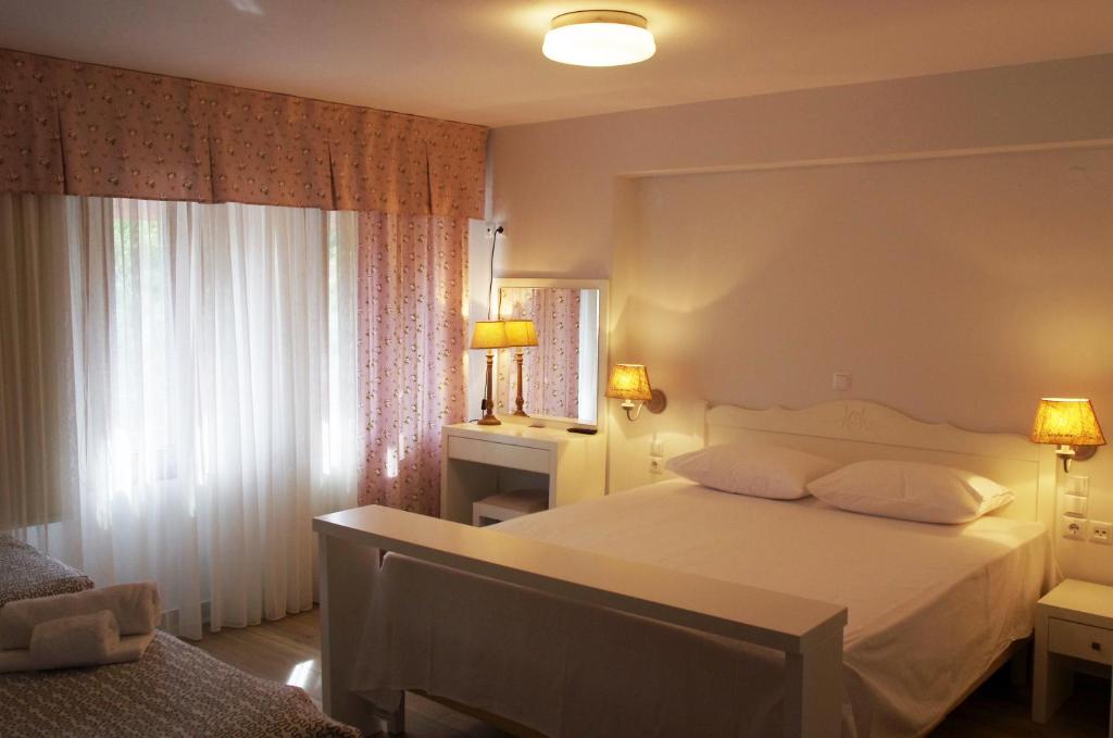 約阿尼納的住宿－Nafsika，卧室配有白色的床和2扇窗户。