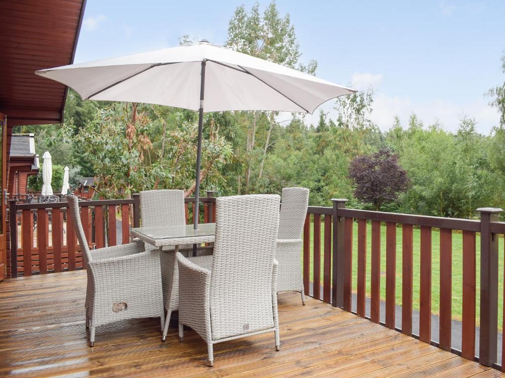 una mesa y sillas con una sombrilla en la cubierta en Lodge 5, en Bridgnorth