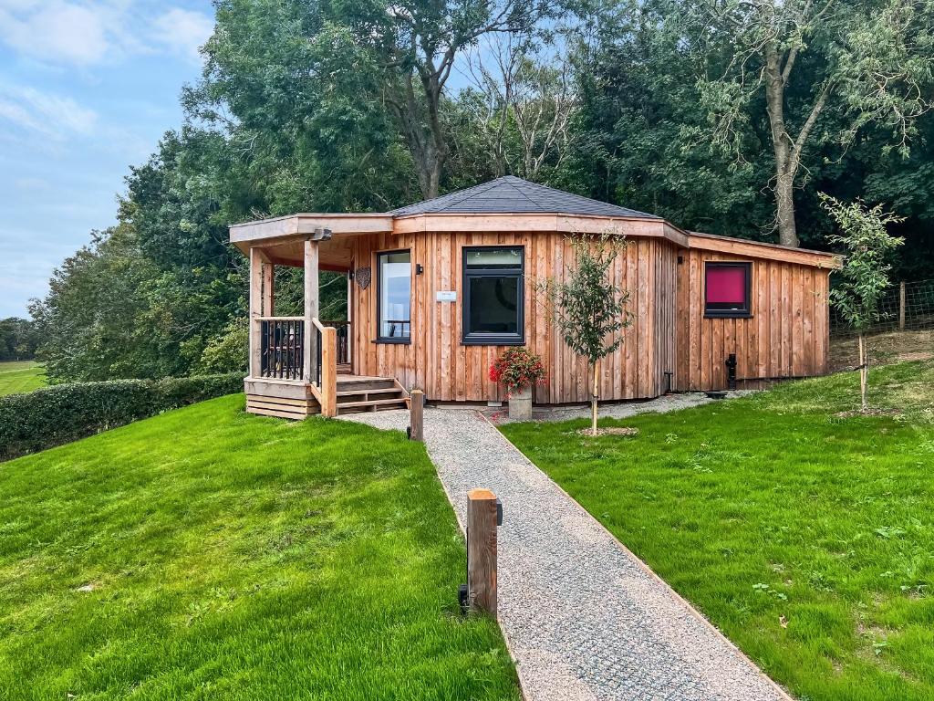 a small wooden cabin in a grassy field at The Nest - Uk50122 in Bodelwyddan