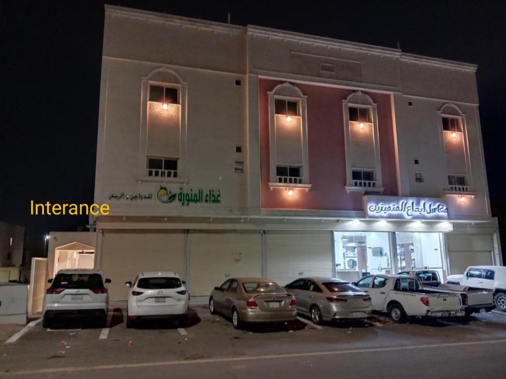 een parkeerplaats met auto's geparkeerd voor een gebouw bij شقق المتميزين in Al Madinah