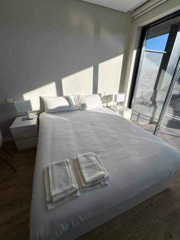 a bedroom with a large white bed with towels on it at New Douro Tower 305 with shared pool in Vila Nova de Gaia