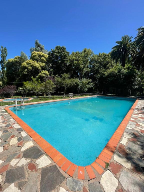 a large swimming pool with blue water at Casa de Campo Brandsen - Quinta La Mandarina in Brandsen