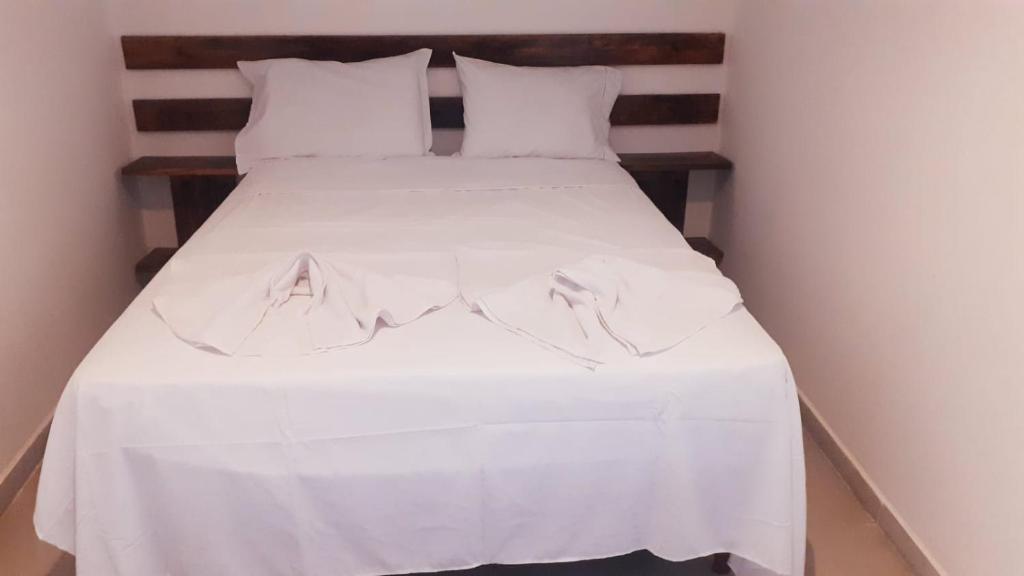 ein weißes Bett mit weißer Bettwäsche und weißen Kissen in der Unterkunft Apartamentos Nova Caraiva in Caraíva