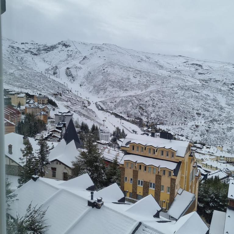 een stad bedekt met sneeuw met een berg op de achtergrond bij COPOS ALTO Elite in Monachil