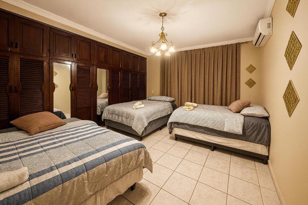 Un dormitorio con dos camas y una lámpara de araña. en Go Bed & Breakfast, en San Pedro Sula