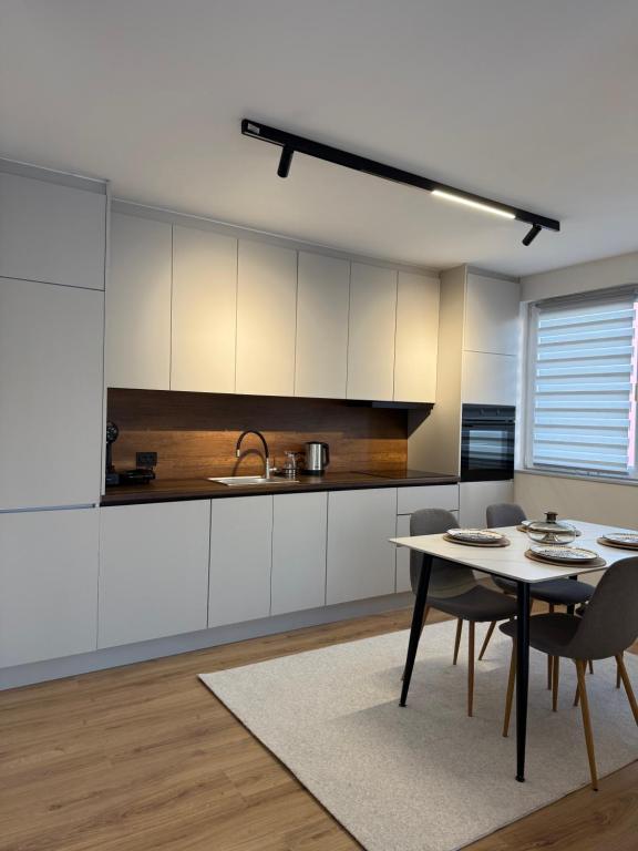 Una cocina con gabinetes blancos y una mesa y sillas. en City Center Penthouse Mitrovice, en Kosovska Mitrovica