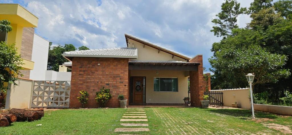 ein kleines Backsteinhaus mit einem Rasenhof in der Unterkunft Casa de Campo com piscina Ninho Verde 2 in Pardinho