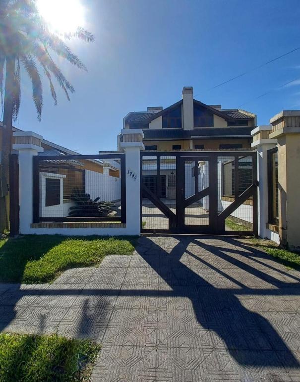 a house with a gate and a palm tree at Sobrado em Imbé - RS in Imbé