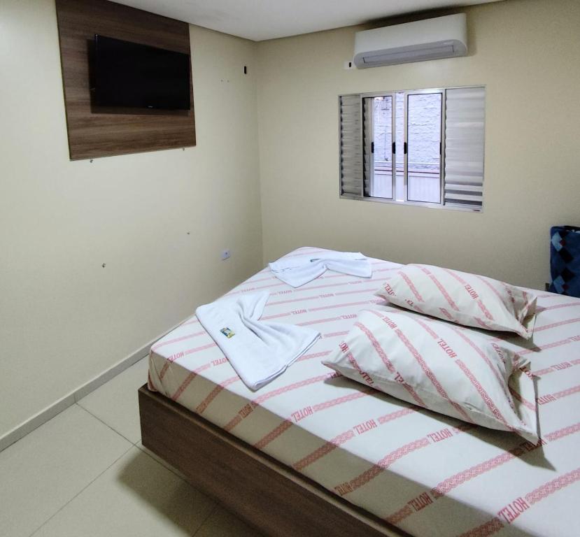una cama en una habitación con un televisor en la pared en Hotel-Motel Novo Oasis, en São Paulo