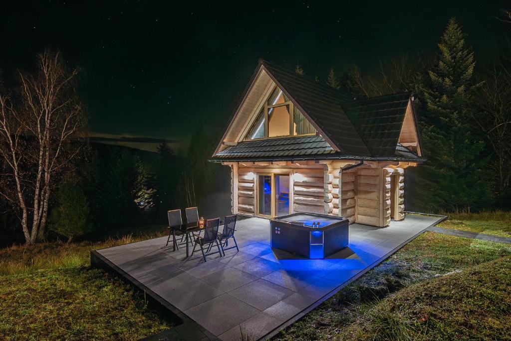 a small log cabin at night with a table and chairs at Zielone Wzgórze Sidzina in Sidzina