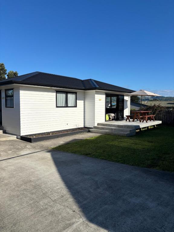 a white house with a black roof at Sun and fun in the Bay - Home away from Home in Porirua