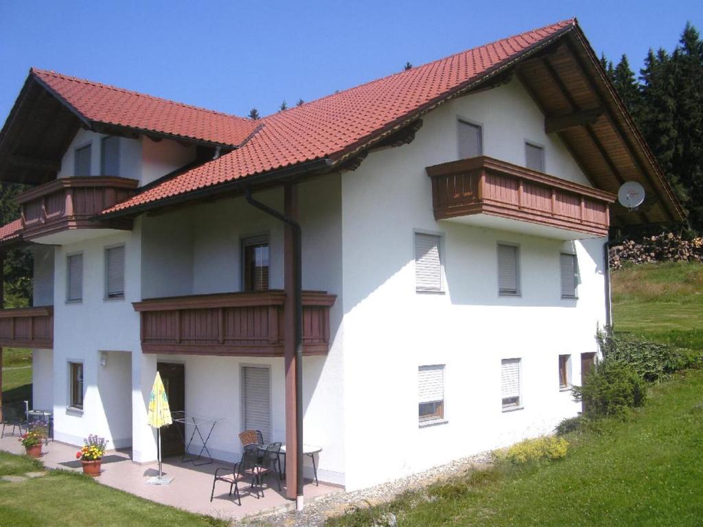 Un grand bâtiment blanc avec un balcon est à votre disposition. dans l'établissement Haidberg-Hof, à Sankt Englmar