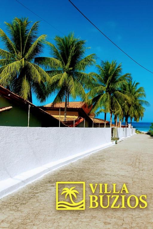 a sign on a beach with palm trees in the background at Villa Búzios in Nísia Floresta