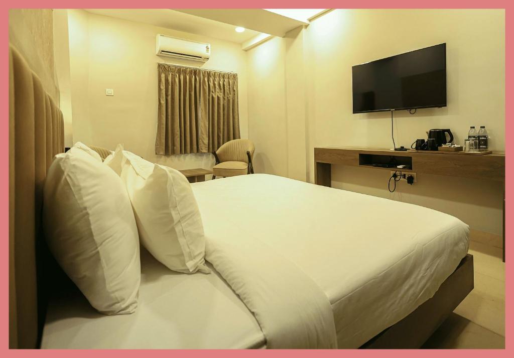 Una habitación de hotel con una cama con almohadas blancas y un televisor. en Sea Shell Residency, en Puri