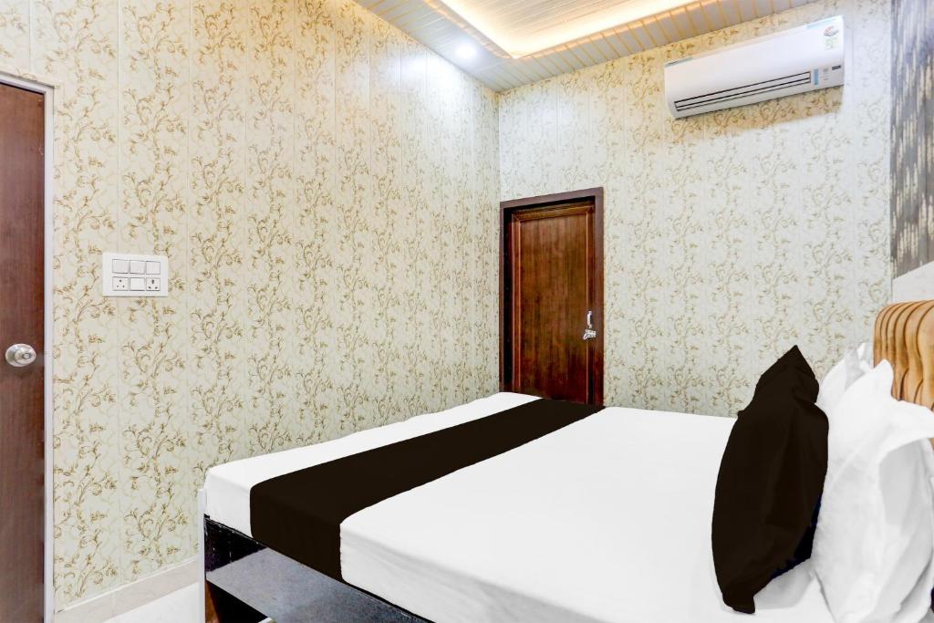 a bedroom with a white bed and a brown door at Super Hotel O Radha kunj By Namasya Retreat International in Prayagraj
