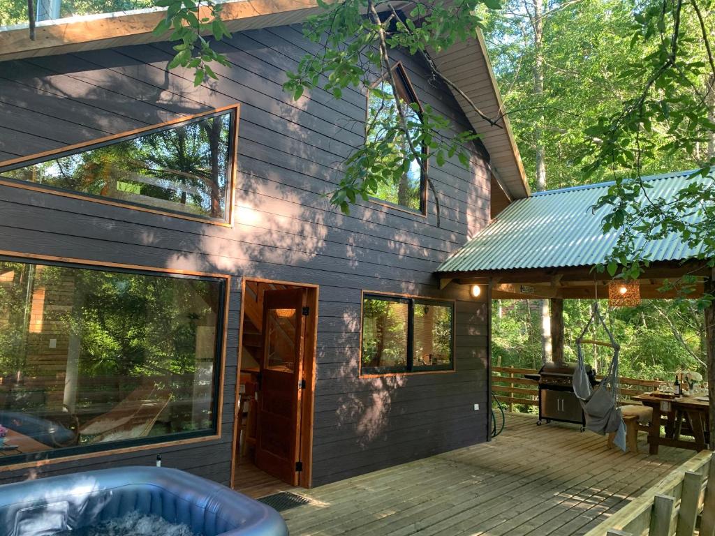 Cabaña Bosque Río في بوكون: منزل به شرفة أمامها حوض استحمام