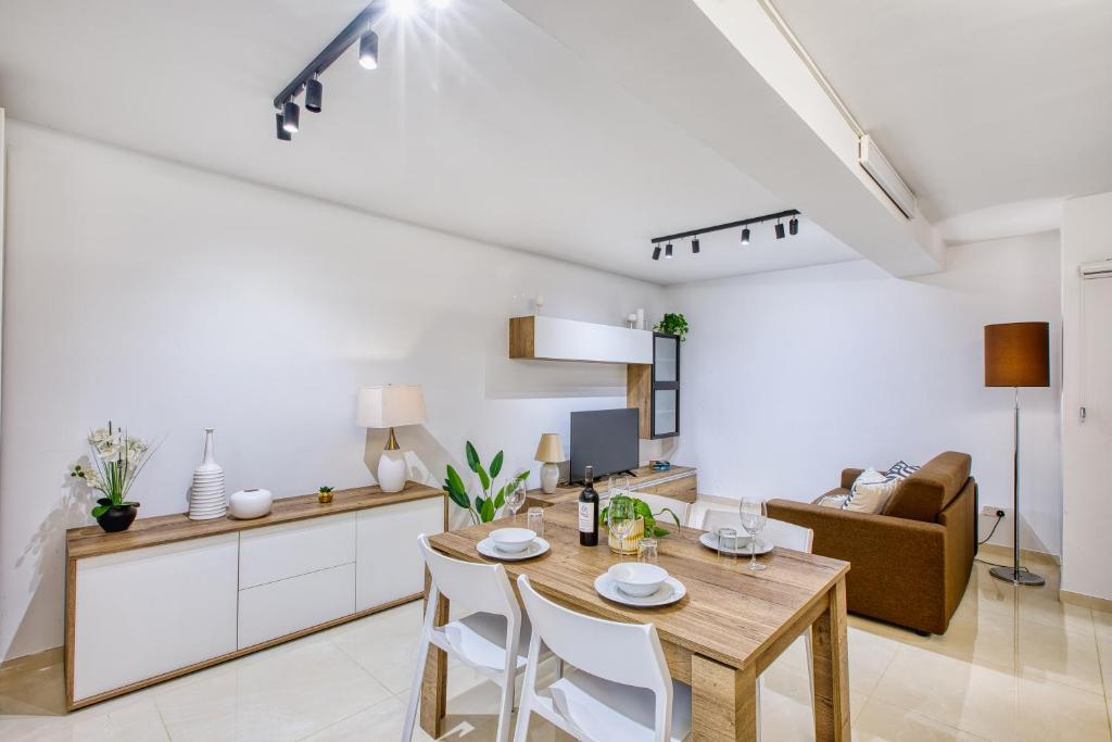 a kitchen and living room with a wooden table and chairs at Cozy 1 Bedroom Maisonette near Ta Xbiex Marina in Taʼ Xbiex