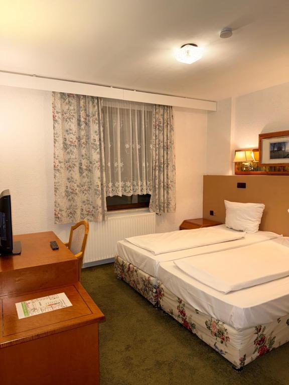 a bedroom with a bed and a desk and a window at Yeti City Hotel Saarbrücken in Saarbrücken