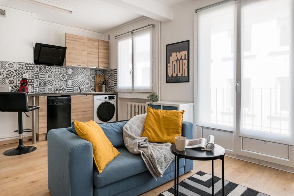 サン・テティエンヌにあるCozy appartement au centre de Saint-Etienneの青いソファとキッチンのあるリビングルーム