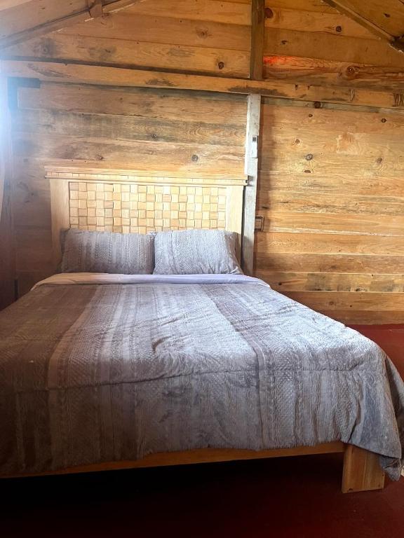 a bed in a room with a wooden wall at La cabaña in Tlazala de Fabela